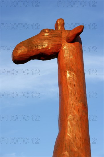 Head and neck of a giraffe made of red painted tree trunks, wooden sculpture by Günter Schumann,