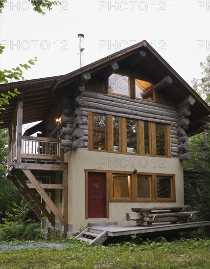 Three story Scandinavian hybrid style log cabin home facade cladded with beige stucco finish and