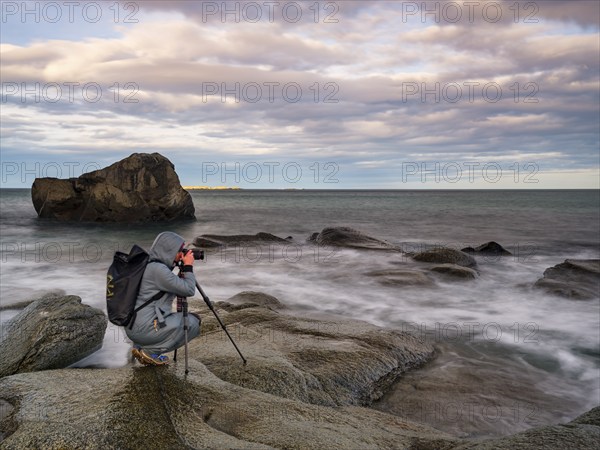 Photographer with tripod on smooth rocks by the sea, Utakleiv, Vestvågøya, Lofoten, Norway, Europe