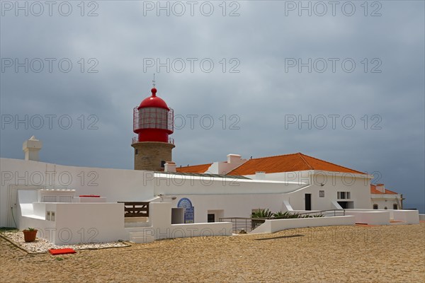 A white building with a red lighthouse under a cloudy sky, Cape St Vincent, Cape St Vincent, Cabo