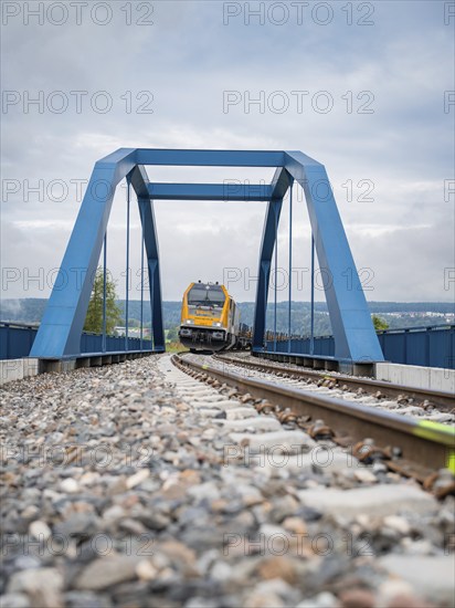 Railway train crossing a blue bridge on a cloudy day, track construction, rail delivery for Hermann
