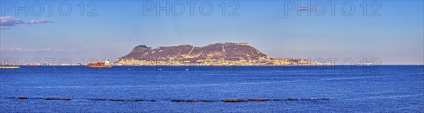 Clear sea with an island in the background and passing ships under a blue sky, Algeciras