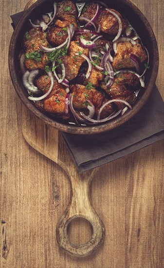 Fried meat, pork kebab, ketsi in a clay pan, with red onions and herbs, homemade, no people