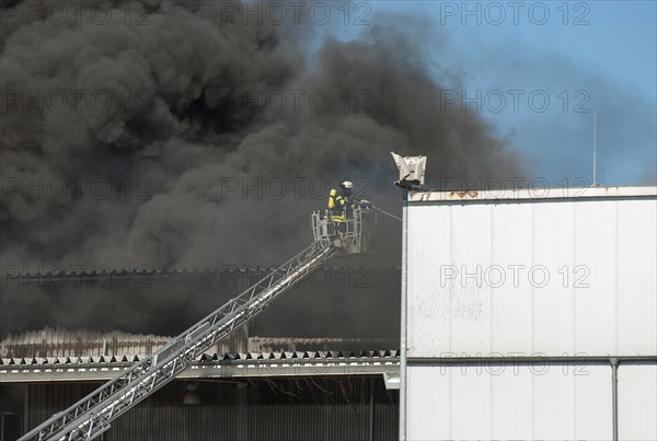 Firefighters in protective clothing in aerial work platform, aerial platform fighting fire in an