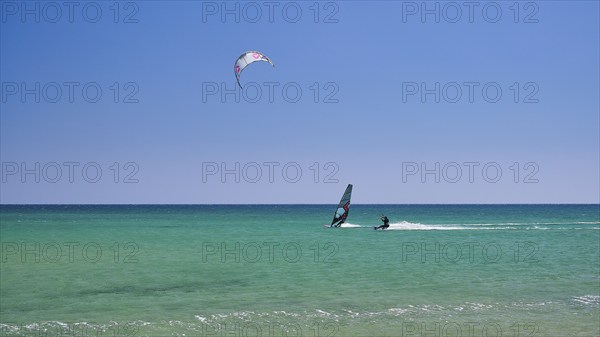 A person windsurfing in a clear blue sea under a sunny sky, surfers paradise, kitesurfer,