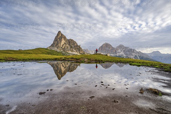 Reflection of the mountains at Passo di Giau, Monte Ragusela, woman with red rucksack, Dolomites,
