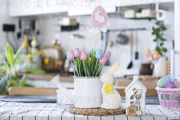 Key to house of cozy home with Easter decor with rabbit and eggs on table of kitchen. Building,