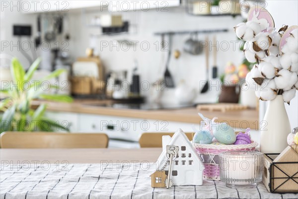 Key to house of cozy home with Easter decor with rabbit and eggs on table of kitchen. Building,