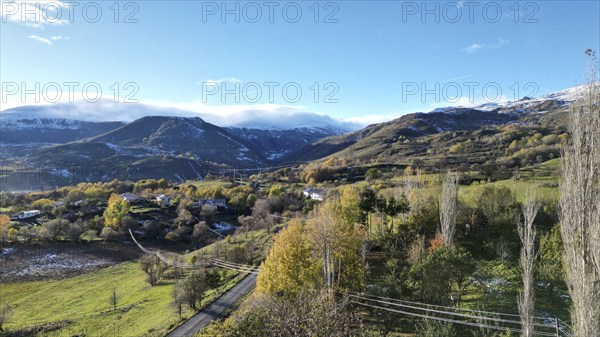 A scenic valley with mountains, scattered trees, and a clear blue sky, capturing a serene winter