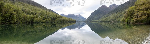 Tranquil lake Gunn in Fiordland National Park, landscape reflecting on the water surface, South