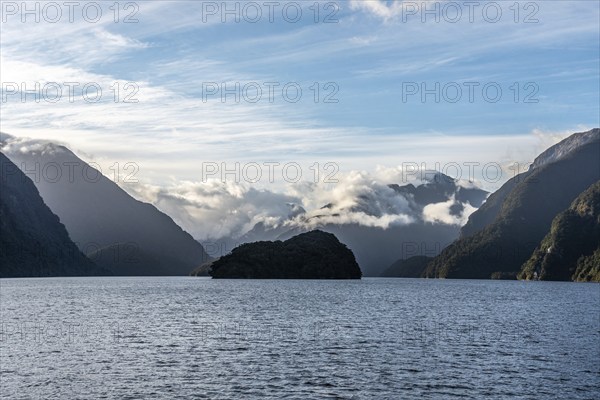 Sun rising over Doubtful Sound, Clouds hanging low on the mountains, South Island of New Zealand