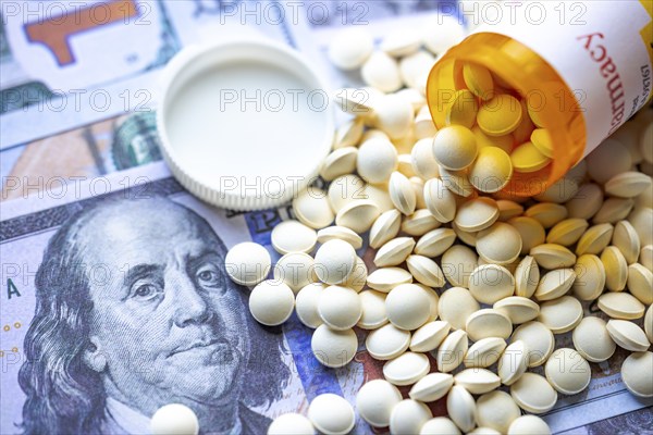 An open medicine pill container on American bills. Concept: American opioid crisis or American