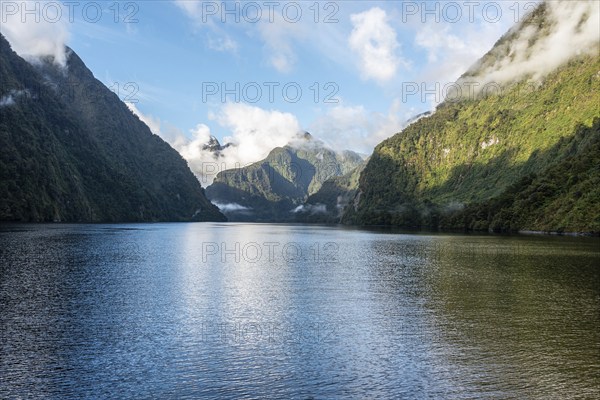 A new morning dawning at Doutful Sound, clouds hanging low in the mountains, South Island of New