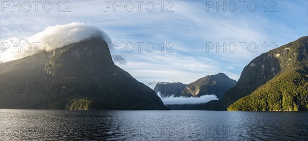 Sun rising over Doubtful Sound, Clouds hanging low on the mountains, South Island of New Zealand
