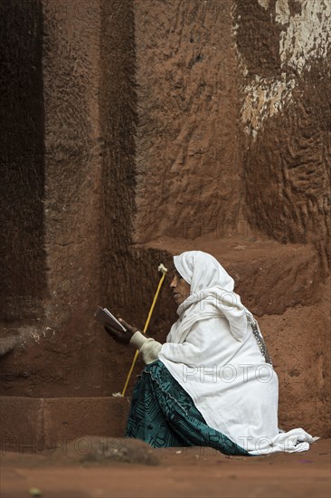 Ethiopian Orthodox woman prays at the entrance to the rock-hewn church of Biete Gabriel-Rufael,