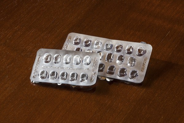 Empty blister packs on a brown wooden surface