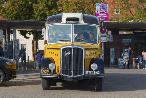 Front view of a yellow vintage bus with people in an urban environment, vintage car, Saurer,