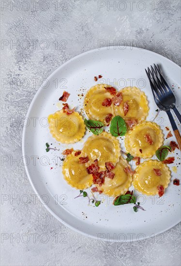 Fresh ravioli, with butter, spices and herbs, fried bacon, on the table, top view, light