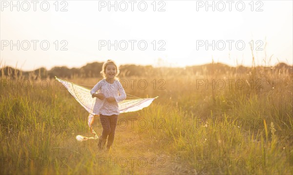 A girl runs into a field with a kite, learns to launch it. Outdoor entertainment in summer, nature