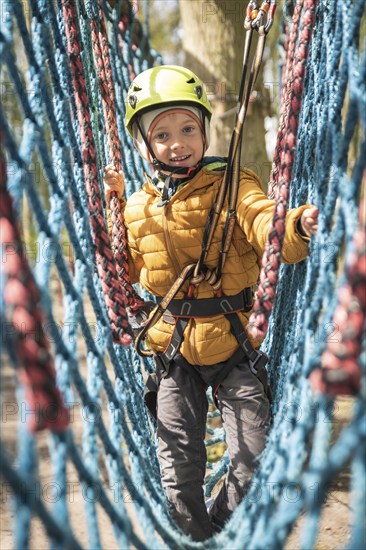 Portrait of cute little boy walk on the net in an adventure rope park