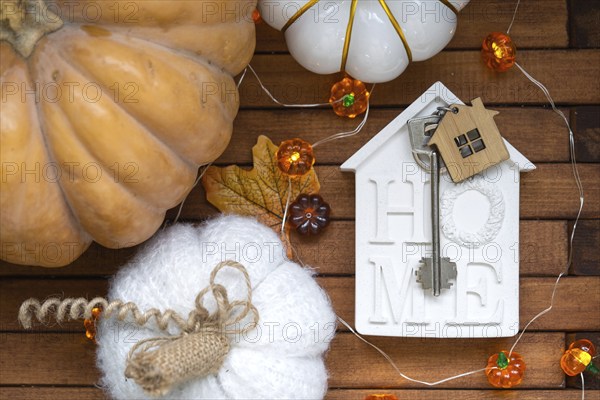 Cozy layout on a wooden background of slats with pumpkins, autumn leaves, a house and keys, autumn