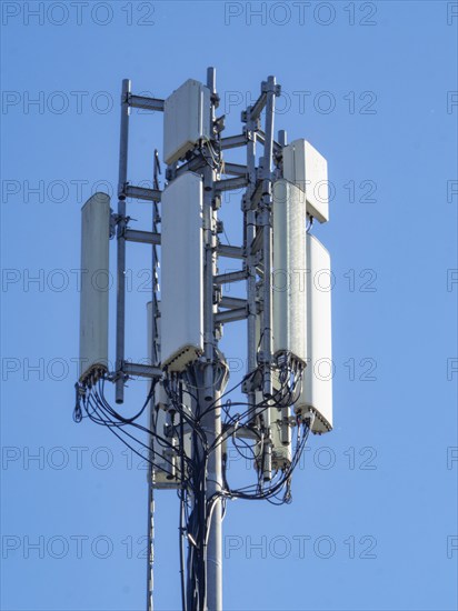 A tall cell tower with multiple antennas against a clear blue sky