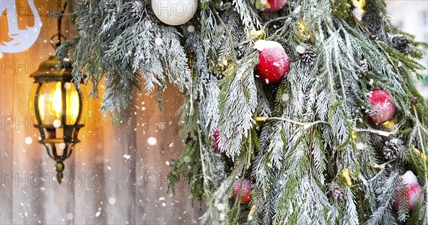 Outdoor Christmas decorations made of natural spruce branches, toys, garlands and a glowing lantern