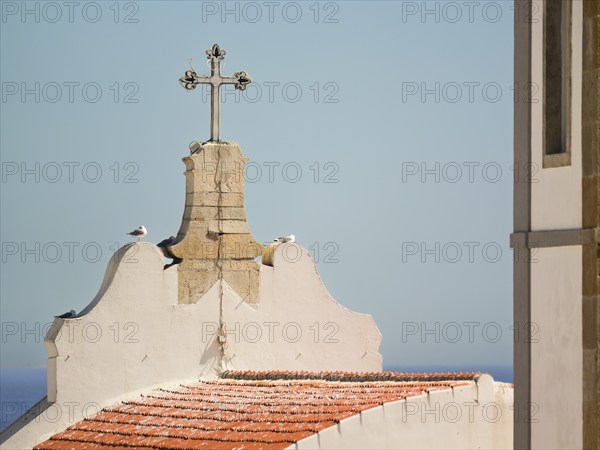 Mother Church cross and rooftop with sky and ocean in the background, Albufeira, Algarve, Portugal,