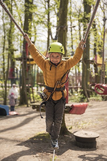 Portrait of cute little boy walk on a rope in an adventure rope park