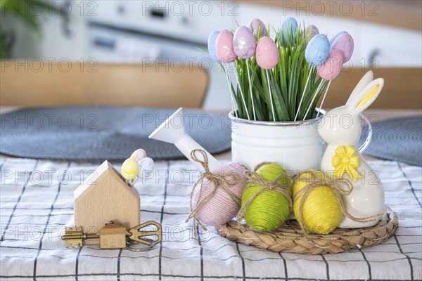 Key to house of cozy home with Easter decor with rabbit and eggs on table of kitchen. Building,
