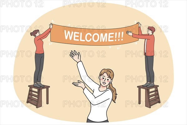Happy people hanging Welcome banner inviting visitors to party or celebration. Smiling hosts