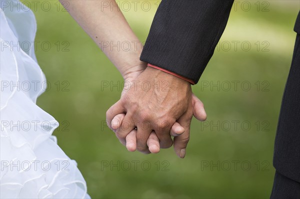 Young married couple holding hands, ceremony wedding day