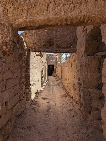Typical abandoned alleyway surrounded by old clay walls in a little village somewhere in the Draa