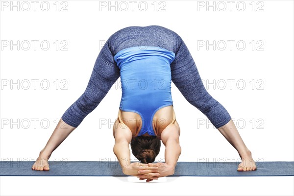 Beautiful sporty fit woman practices Ashtanga Vinyasa yoga asana Prasarita padottanasana C, wide