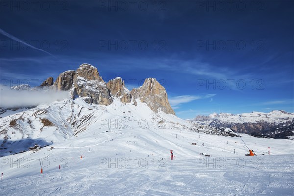 View of a ski resort piste with people skiing in Dolomites in Italy