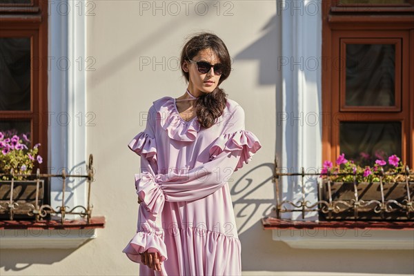 Outdoor urban portrait of young beautiful stylish girl in oversized pink dress