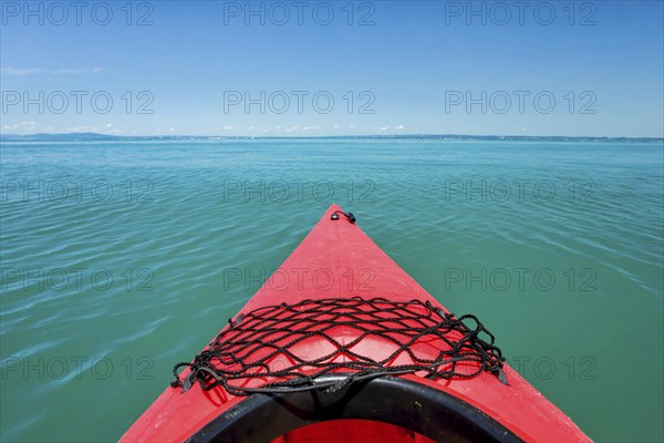 Bow of red kayak with view over the expanse and turquoise waters of Lake Constance