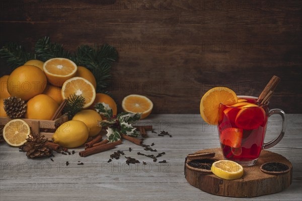 Wooden basket with oranges and lemons, punch in glass cup, cloves and cinnamon sticks, Christmassy,