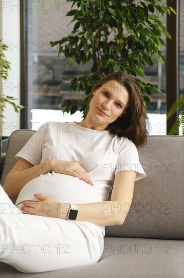 Beautiful pregnant woman having rest on sofa at home