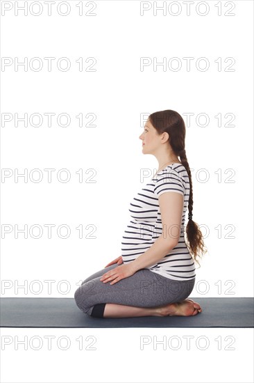 Pregnancy yoga exercise, pregnant woman doing yoga asana Virasana Hero Pose on knees isolated on