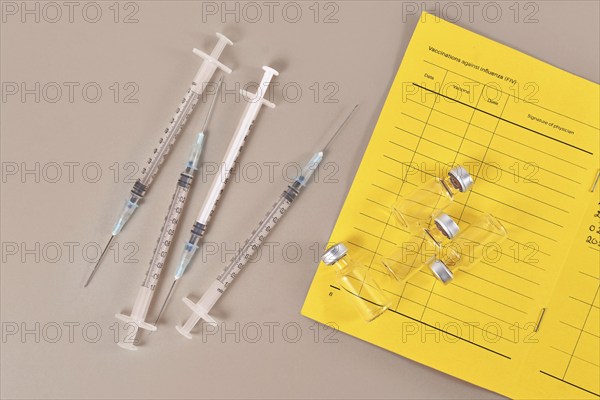 Concept for Corona virus booster vaccination showing vaccine passport with 4 syringes and vials