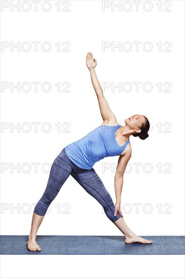 Beautiful sporty fit woman practices yoga asana utthita trikonasana, extended triangle pose