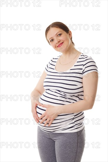 Pregnant smiling woman standing embracing her belly isolated on white background
