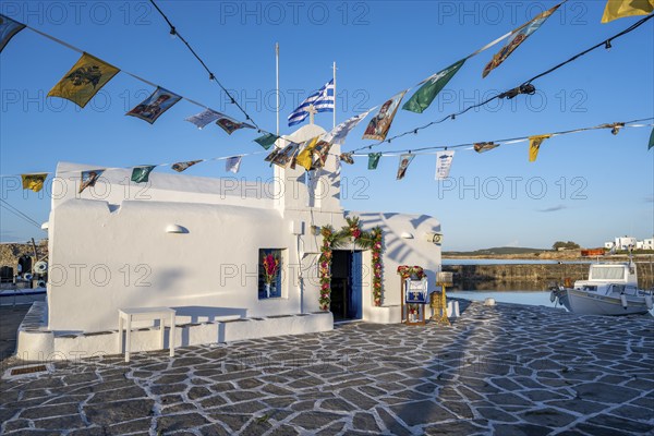 White Cycladic Greek Orthodox Church of Agios Nikolaos, decorated with flags, harbour of Naoussa,