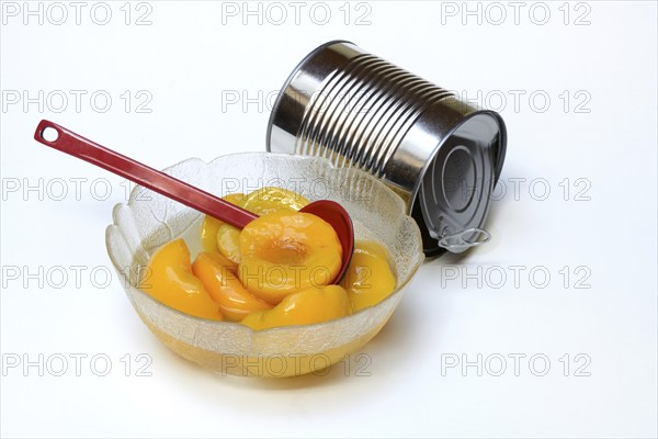Peach, pickled peach halves in glass bowl with ladle and preserving tin