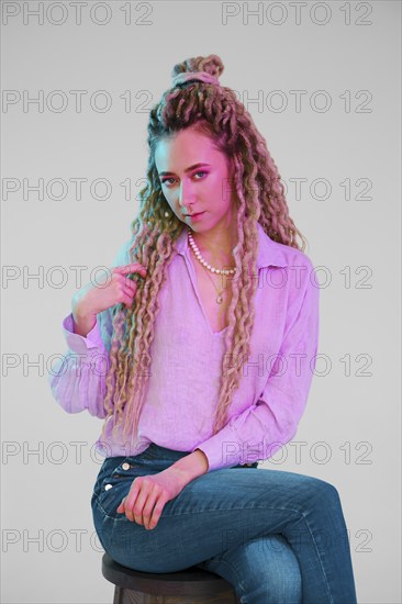 Young woman touching her dreadlocks and looking forward