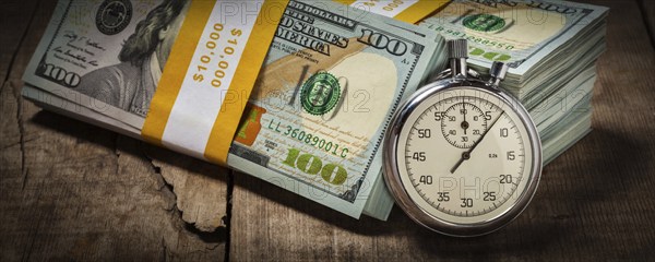 Time is money loan concept background, letterbox panorama of stopwatch and stack of new 100 US