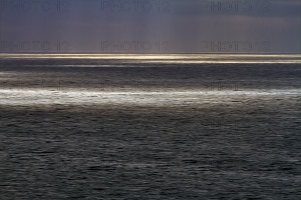 Sunbeams through cloud cover, sunlight glistening on the sea, evening sky, motion blur,