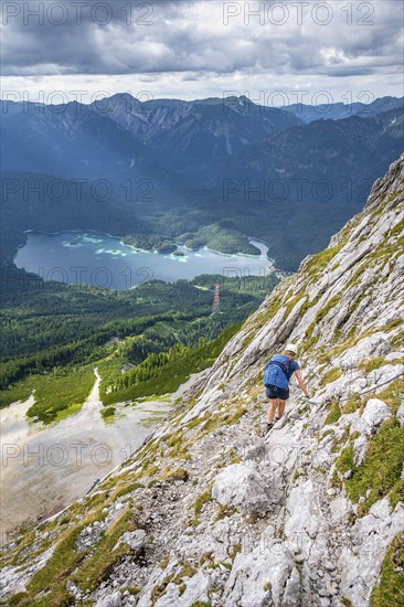 Via ferrata over the Riffelscharte, hiker in the mountains, view of Eibsee lake and Werdenfelser