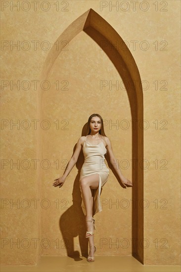 Oriental summer vibe. Cute young woman in silky spaghetti strap dress standing in middle eastern